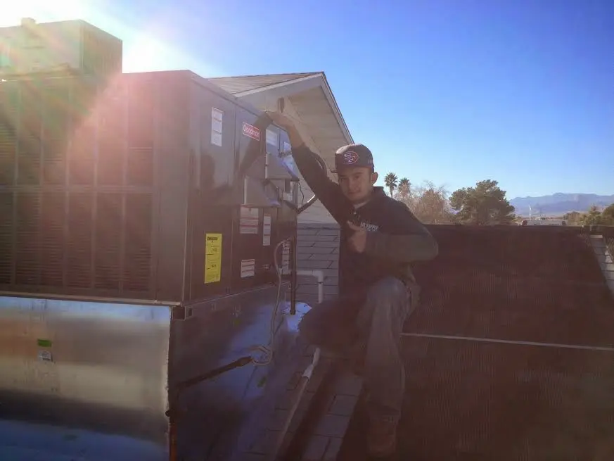 HVAC technician performing Air Duct Cleaning on a rooftop unit in Paxton